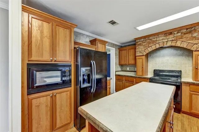 a kitchen with stainless steel appliances granite countertop a refrigerator a stove a sink dishwasher and white cabinets with wooden floor