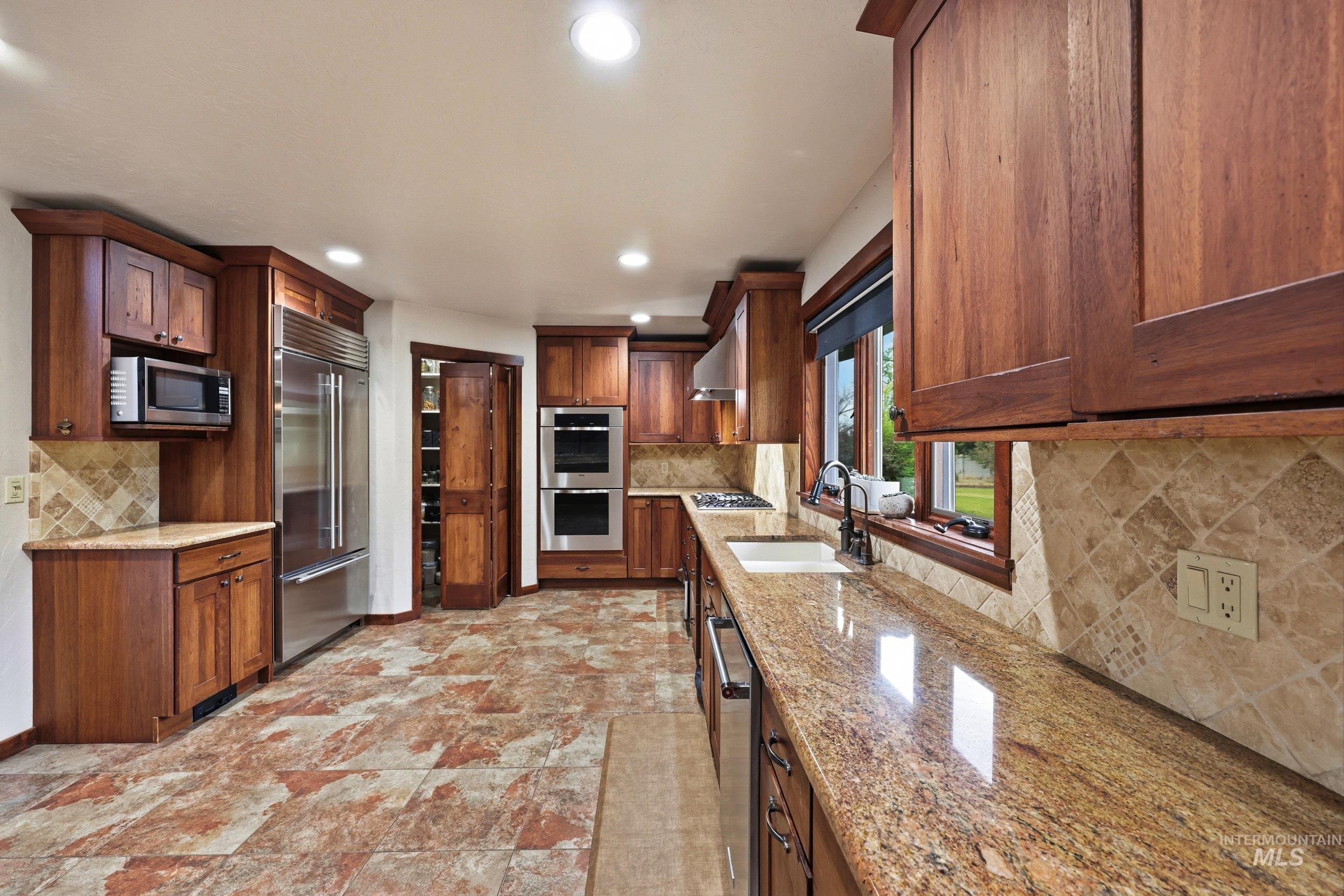 339 Airport Road Weiser, ID 83672 - Photo 15 of 49 Kitchen featuring rich wood cabinetry, stainless steel appliances, granite countertops, a tiled backsplash, and patterned tile flooring