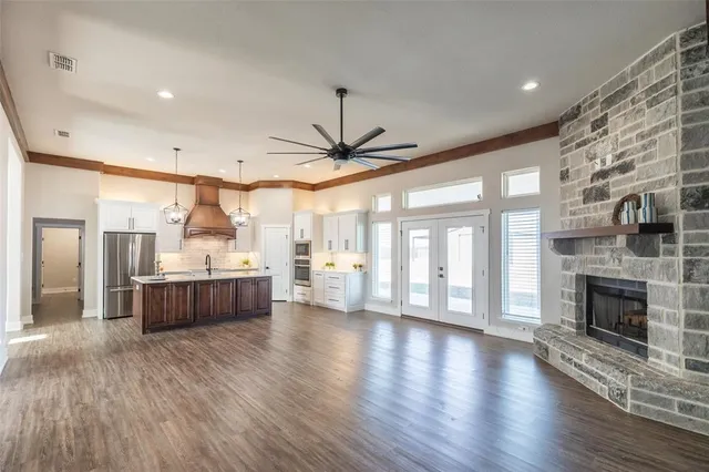 a large living room with stainless steel appliances wooden floors and fireplace