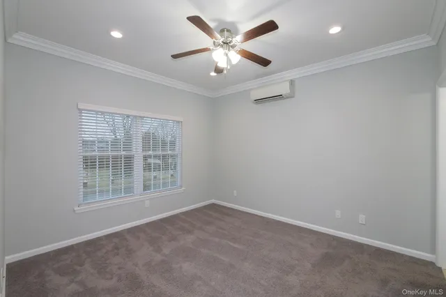 an empty room with chandelier fan and windows