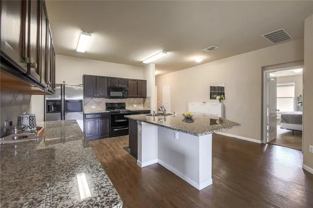 a kitchen with stainless steel appliances granite countertop a sink stove microwave and refrigerator