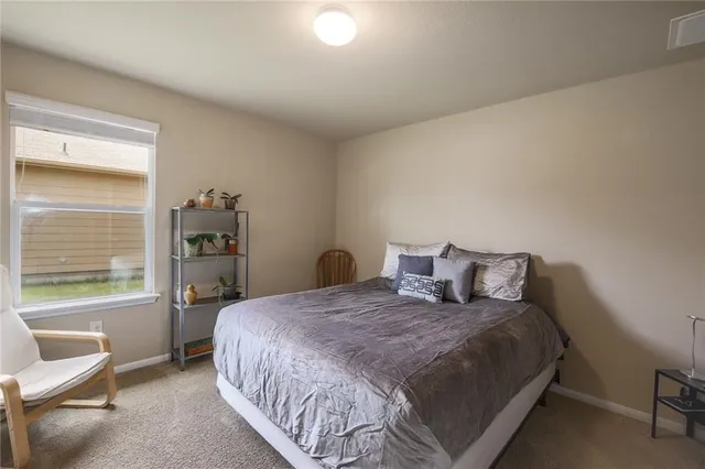 a large bed sitting in a bedroom next to a window and a chair