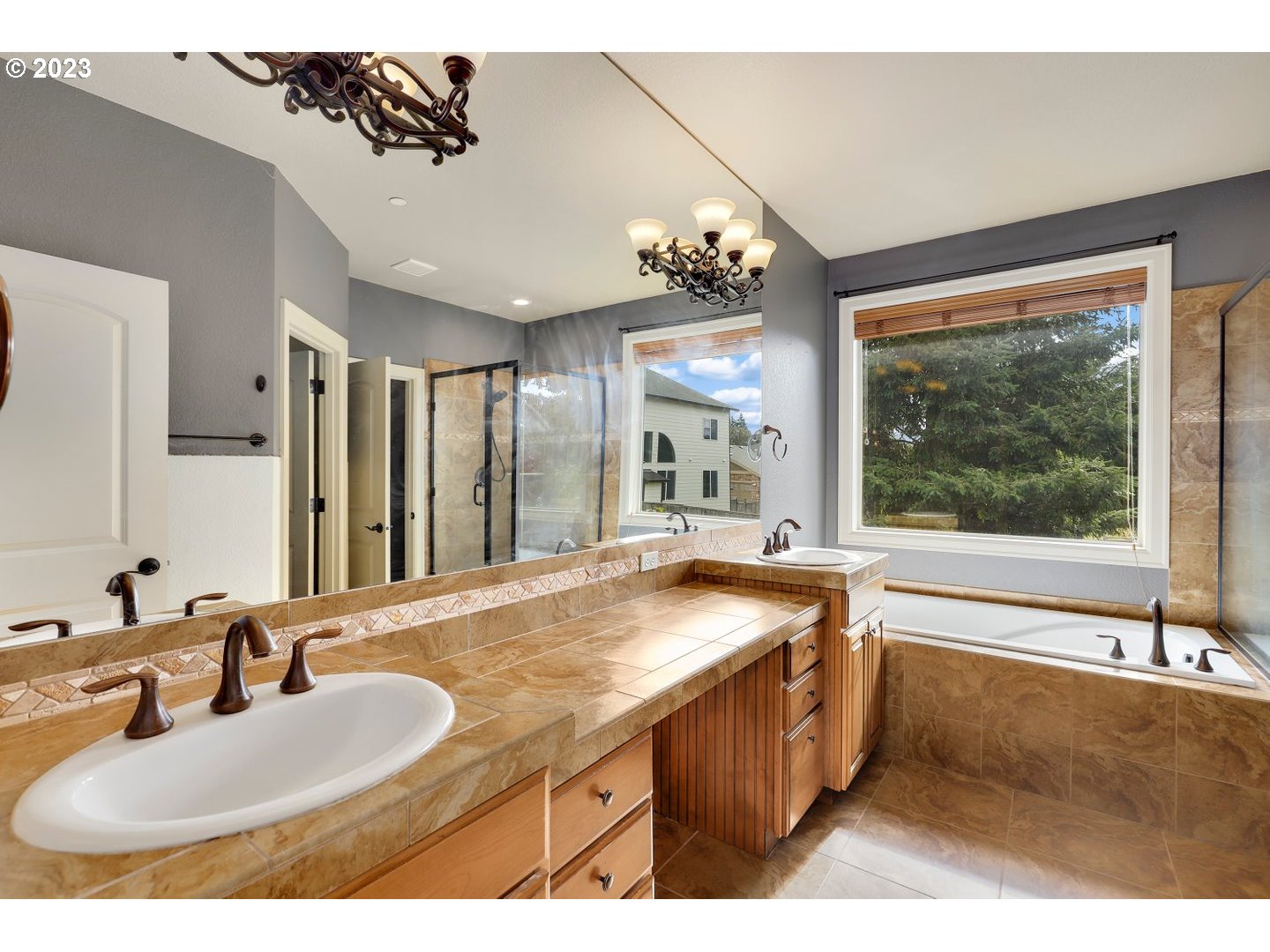 6136 Northwest Larkspur Street Camas, WA 98607 - Photo 23 of 40 a bathroom with a granite countertop sink a large mirror and a bathtub next to a window