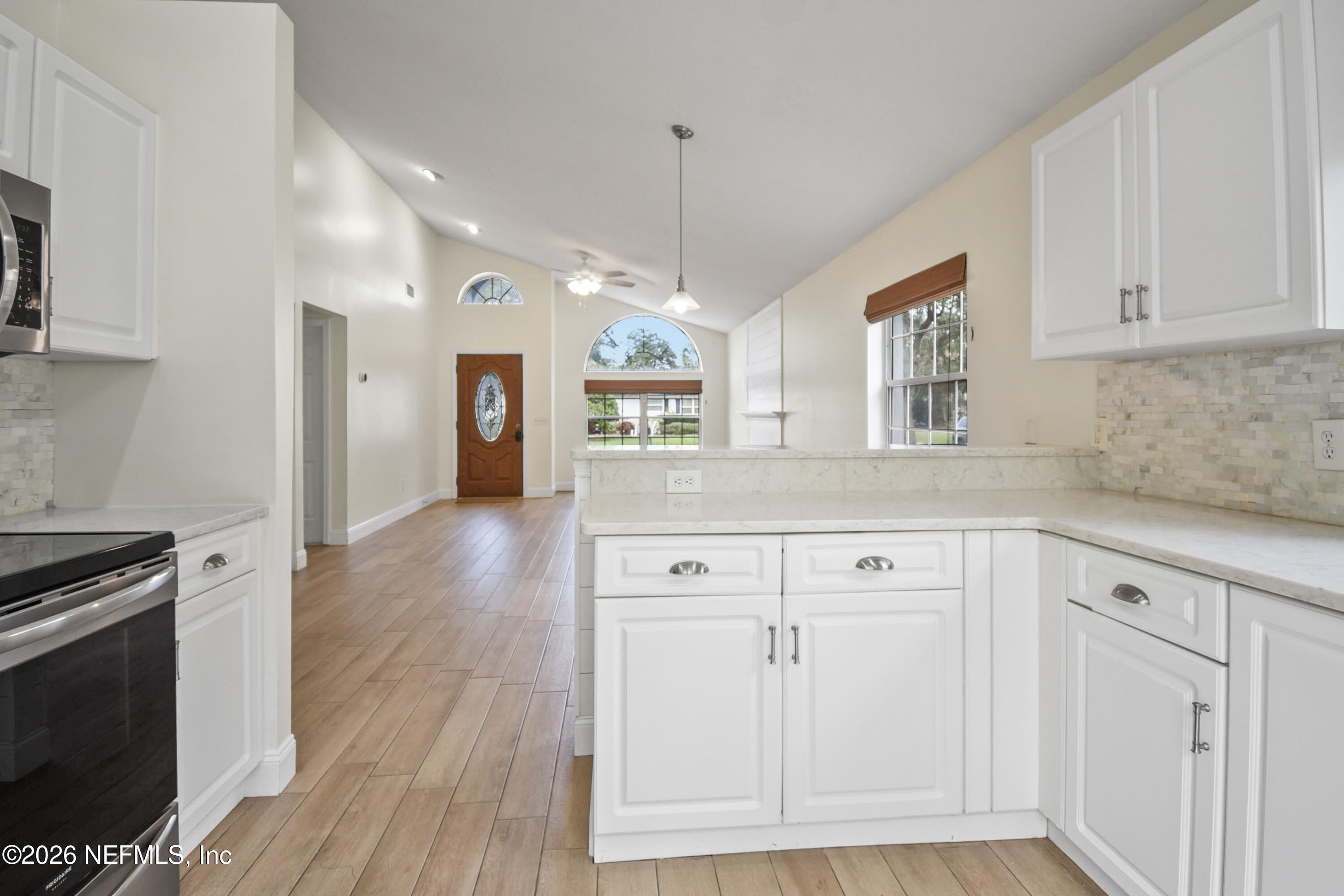 303 D Street St. Augustine Beach, FL 32080 - Photo 16 of 39 a kitchen with stainless steel appliances granite countertop a sink a stove a microwave and wooden floors