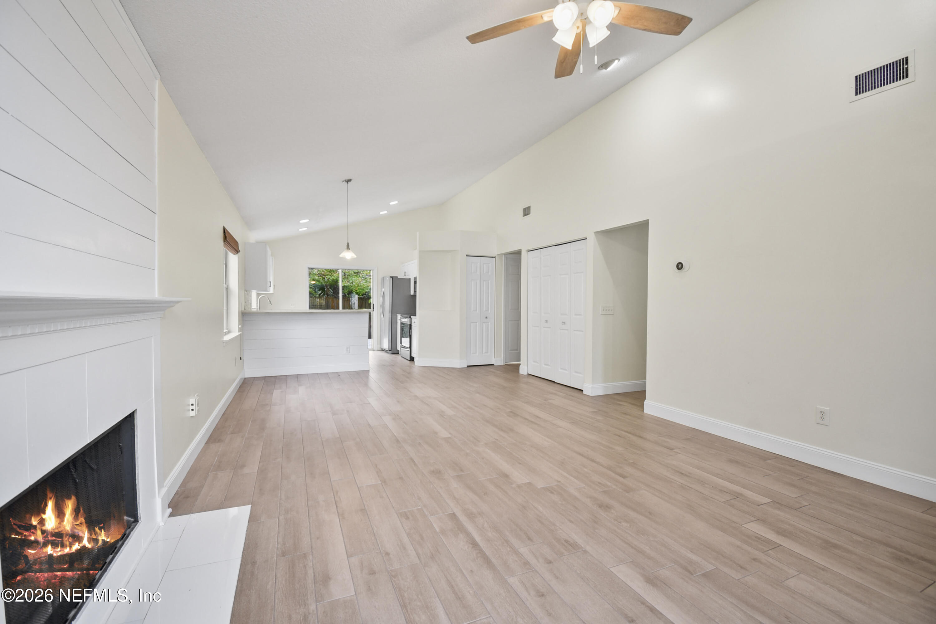 303 D Street St. Augustine Beach, FL 32080 - Photo 10 of 39 a view of a livingroom with wooden floor a ceiling fan and a kitchen