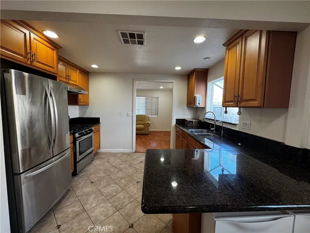 a kitchen with stainless steel appliances granite countertop a sink a stove and a refrigerator
