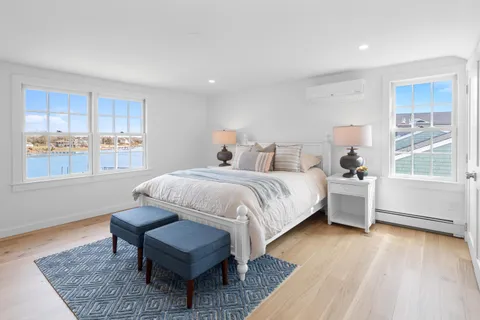 a spacious bedroom with a bed a dresser and wooden floor