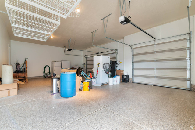 439 East 13540 South Draper, UT 84020 - Photo 35 of 46 Spacious garage featuring a durable epoxy-coated floor, two overhead garage doors, overhead storage racks, and an automatic garage door opener