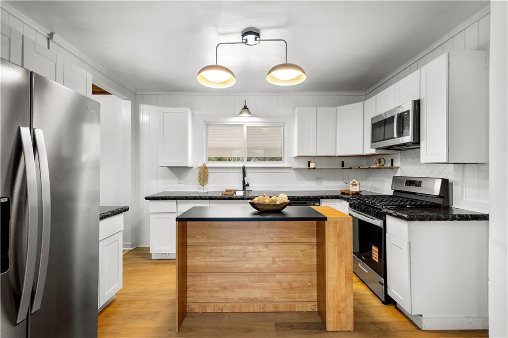 147 Carmichaels Street Rices Landing, PA 15357 - Photo 5 of 36 a kitchen with stainless steel appliances granite countertop a stove top oven a refrigerator a sink and dishwasher with wooden floor