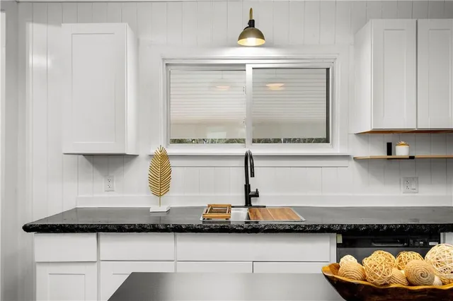 a kitchen with stainless steel appliances granite countertop a stove top oven a sink dishwasher a dining table and chairs with wooden floor