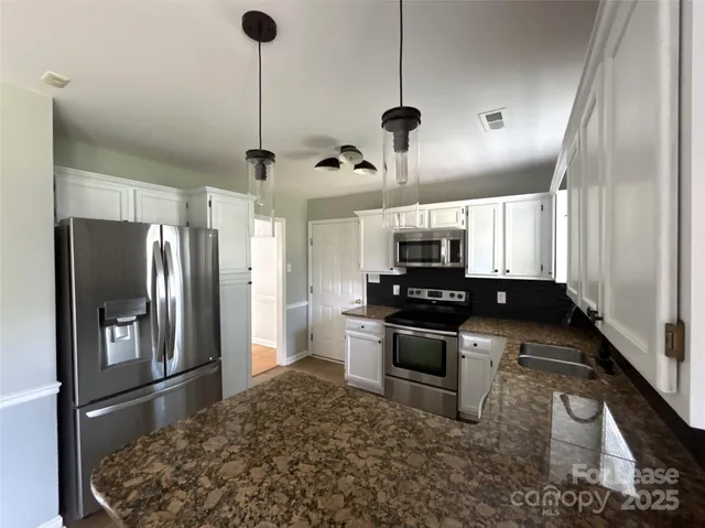 a kitchen with stainless steel appliances granite countertop a sink a stove and a refrigerator