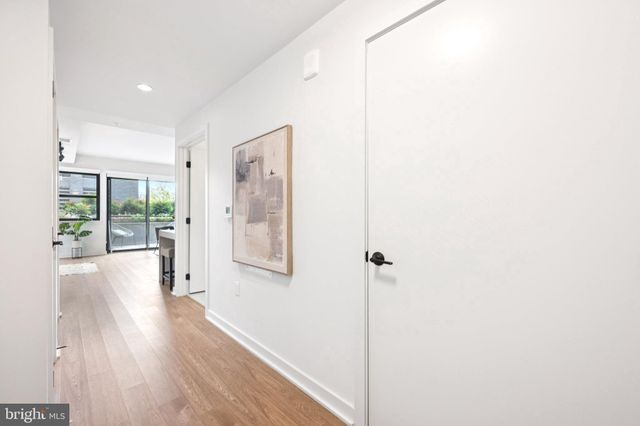 a view of a hallway with wooden floor and a bathroom