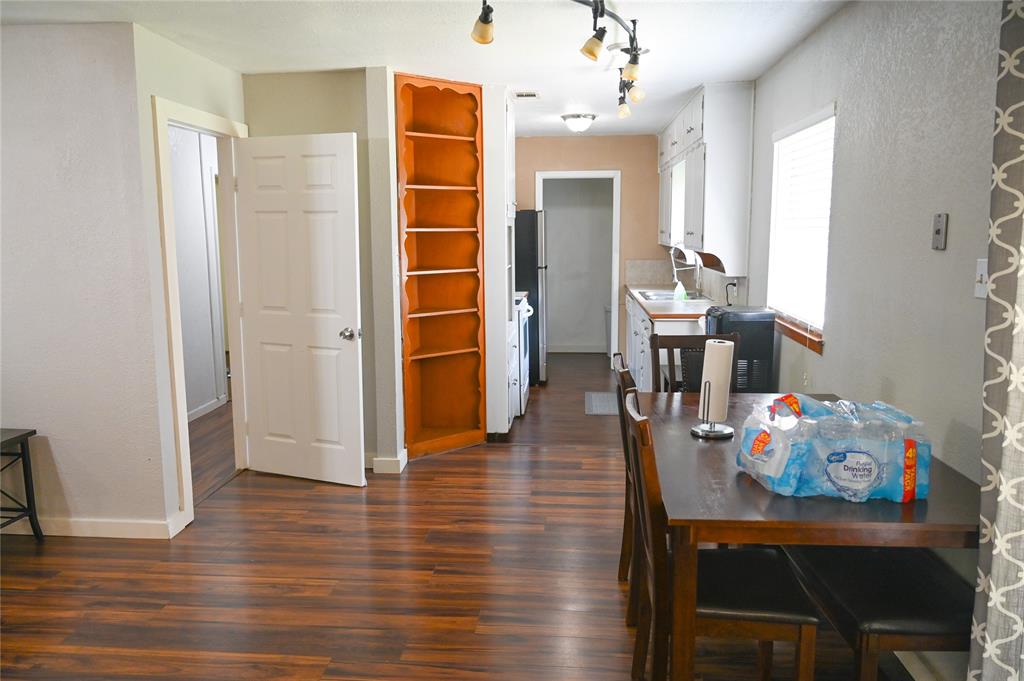 1352 Simpson Drive Hurst, TX 76053 - Photo 37 of 40 Wood-finish flooring extending throughout, built-in shelving, white paneled doors, and track lighting in the kitchen area