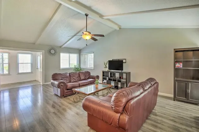 a living room with furniture a ceiling fan and a flat screen tv