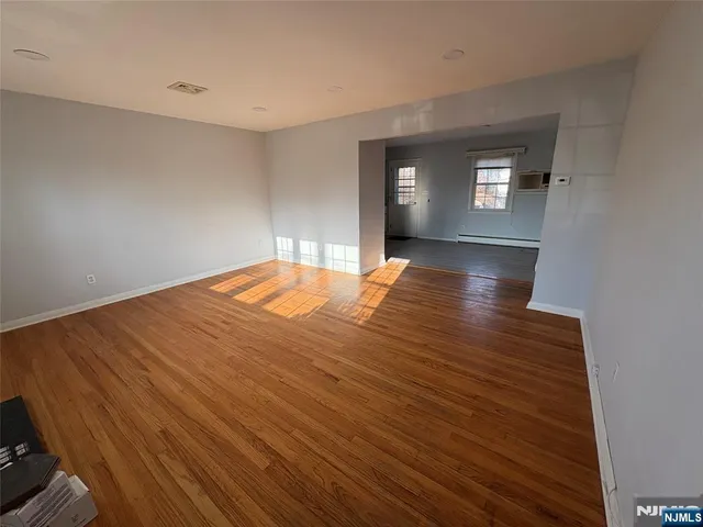 a view of empty room with window and wooden floor