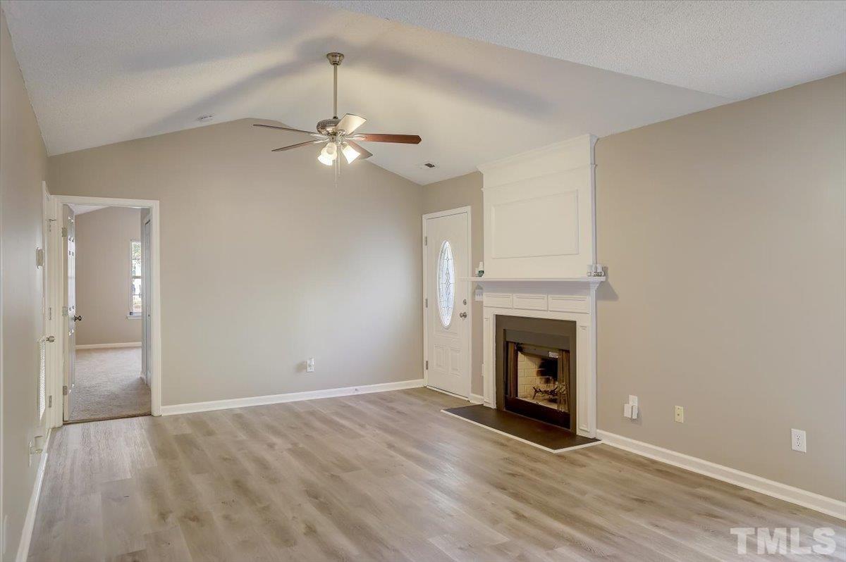 5102 Gable Ridge Drive Durham, NC 27713 - Photo 3 of 17 a view of a livingroom with a fireplace a chandelier fan and wooden floor