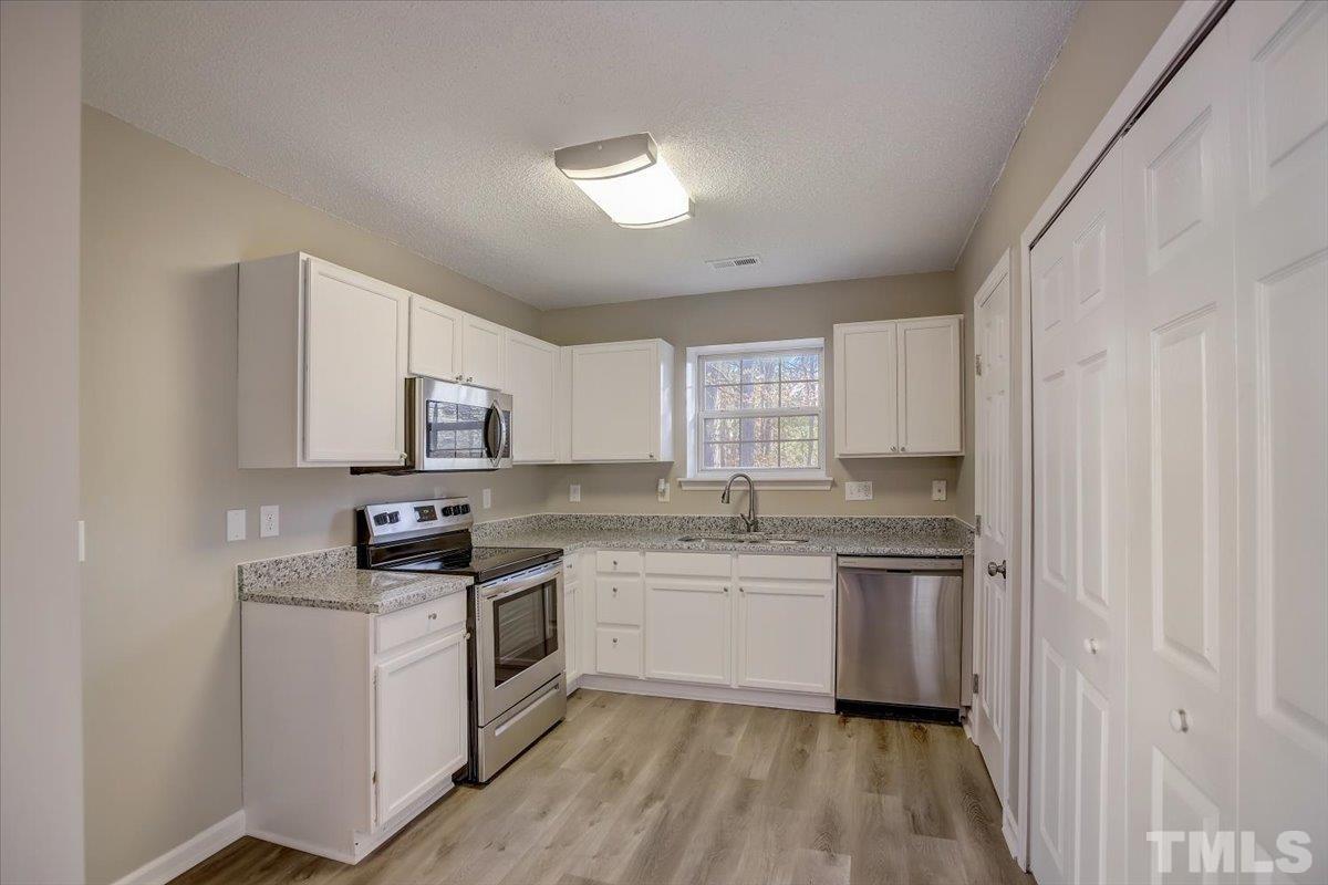 5102 Gable Ridge Drive Durham, NC 27713 - Photo 7 of 17 a kitchen with a sink stove cabinets and refrigerator