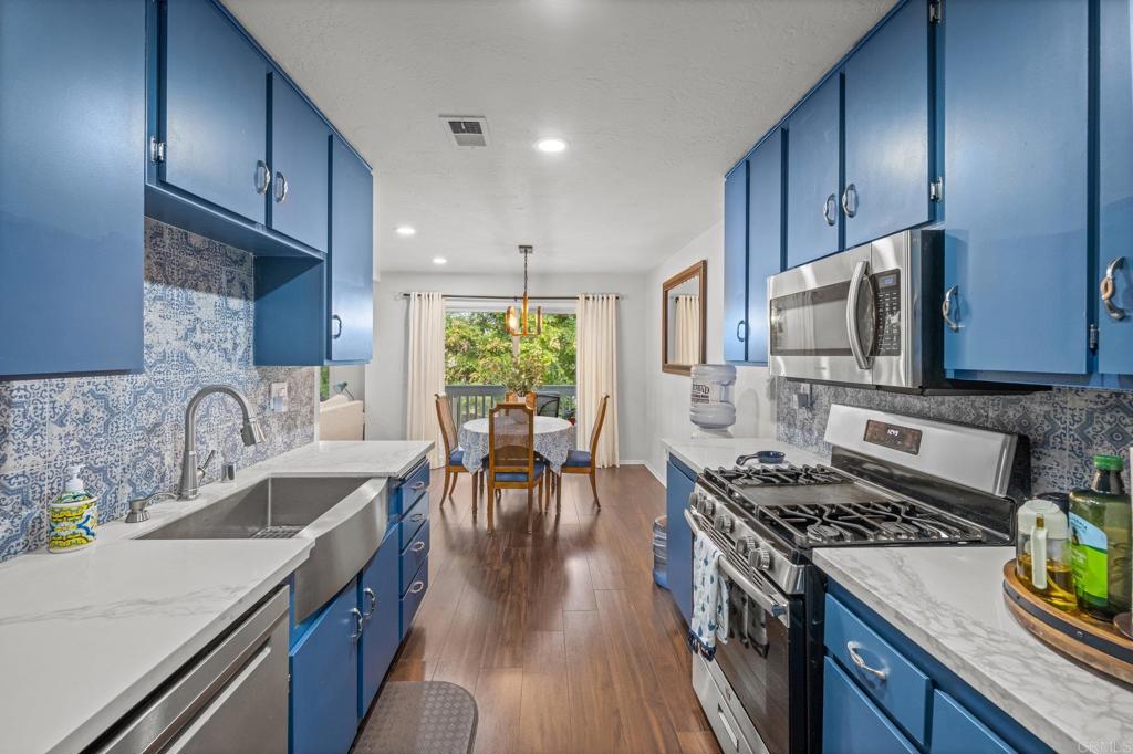 4232 Fiesta Way, Unit 3 Oceanside, CA 92057 - Photo 16 of 33 a kitchen with stainless steel appliances a stove a sink cabinets and a wooden floor