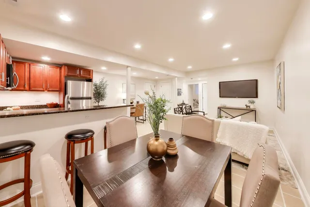 a living room with stainless steel appliances furniture a rug and a kitchen view
