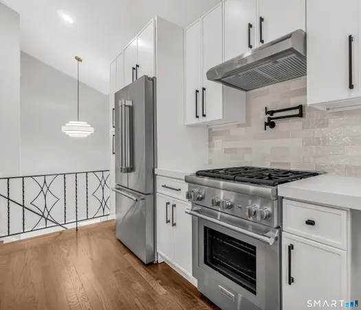 a kitchen with stainless steel appliances granite countertop a stove a refrigerator and a wooden floor