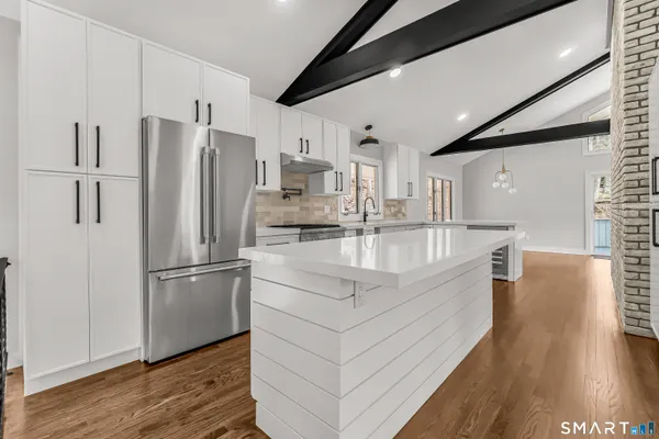a kitchen with stainless steel appliances granite countertop a refrigerator a sink and a stove