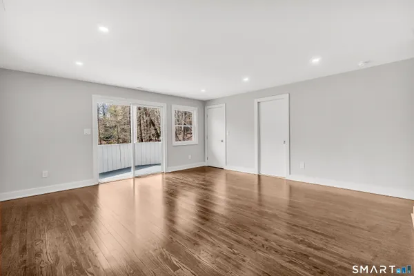 a view of an empty room with wooden floor and a window