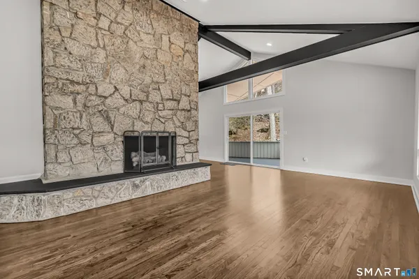 a view of an empty room with wooden floor fire place