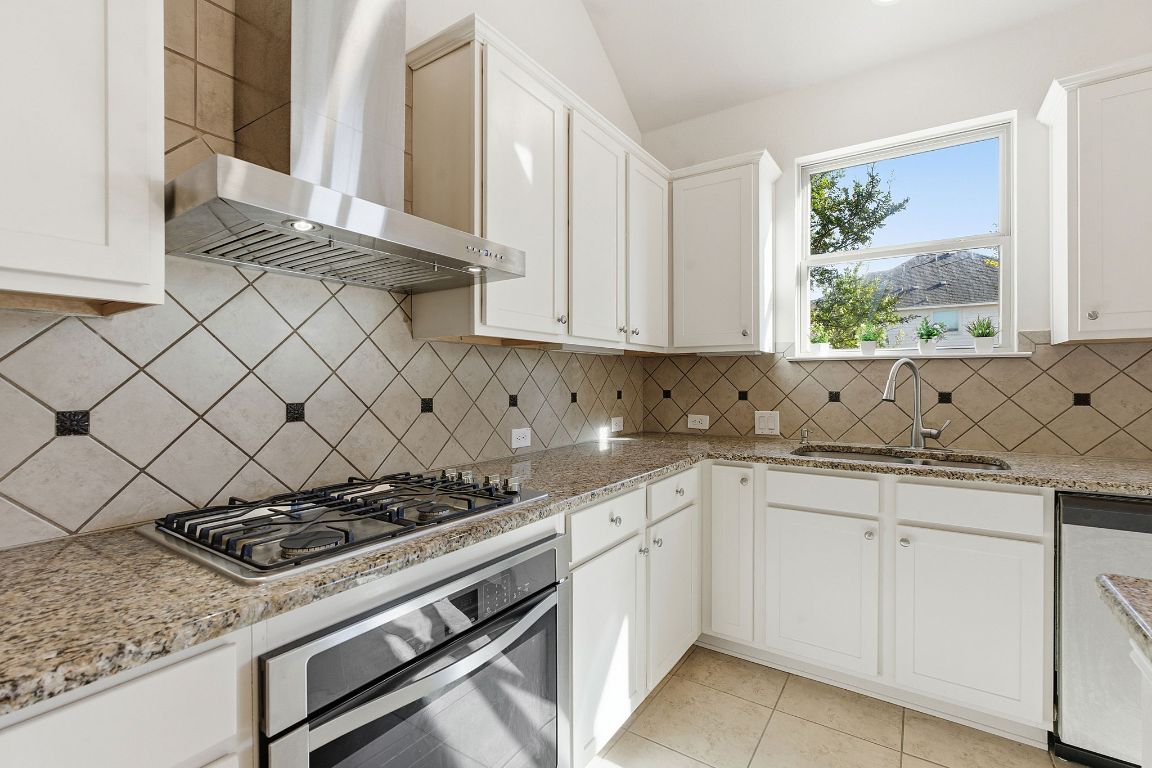 21100 Windmill Ranch Avenue Pflugerville, TX 78660 - Photo 6 of 29 a kitchen with white cabinets and appliances