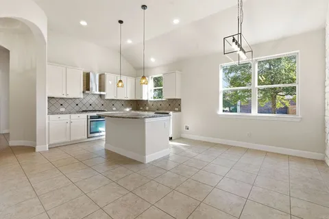 a kitchen with stainless steel appliances granite countertop a stove top oven a sink a counter top space cabinets and a window