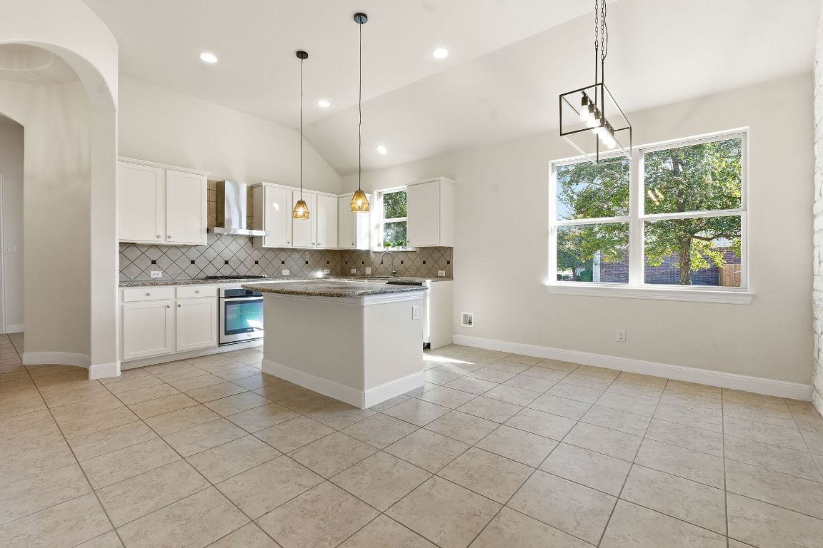 21100 Windmill Ranch Avenue Pflugerville, TX 78660 - Photo 7 of 29 a kitchen with stainless steel appliances granite countertop a stove top oven a sink a counter top space cabinets and a window