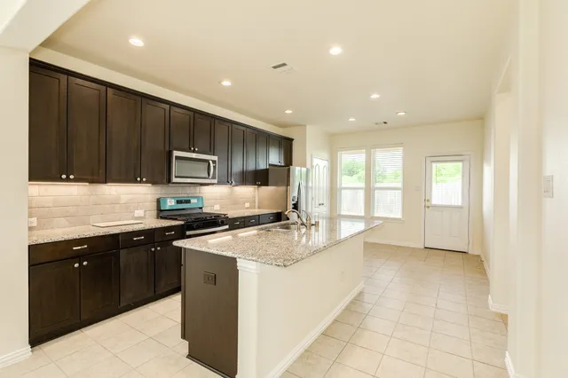 a kitchen with stainless steel appliances granite countertop a sink stove and cabinets