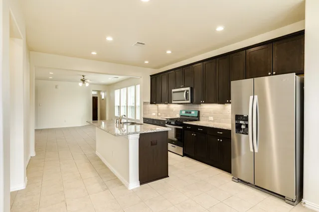 a kitchen with stainless steel appliances granite countertop a refrigerator and a stove