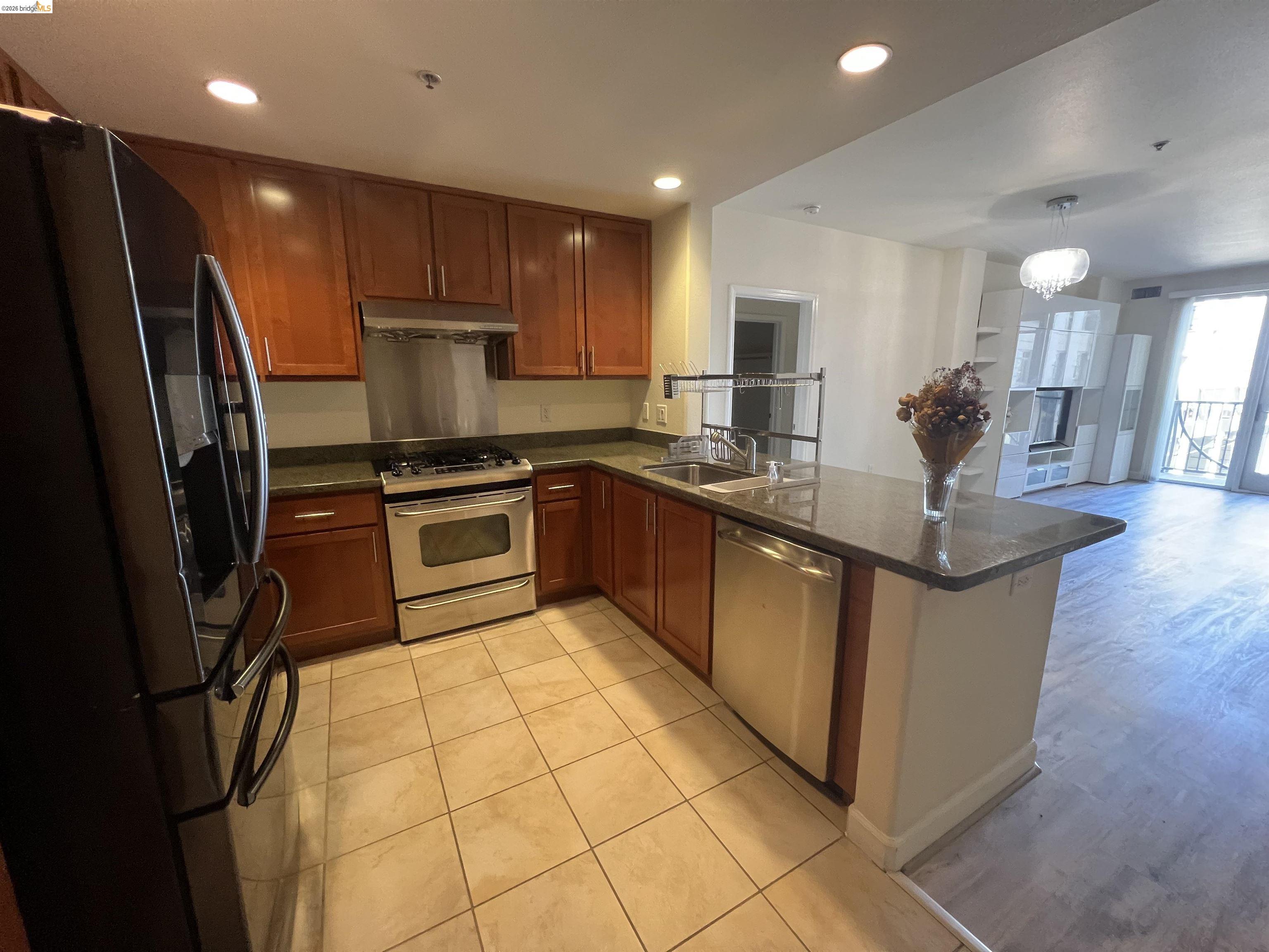 423 7th Street, Unit 313 Oakland, CA 94607 - Photo 4 of 11 Kitchen featuring wood cabinetry, stainless steel appliances, dark countertops, and tile flooring