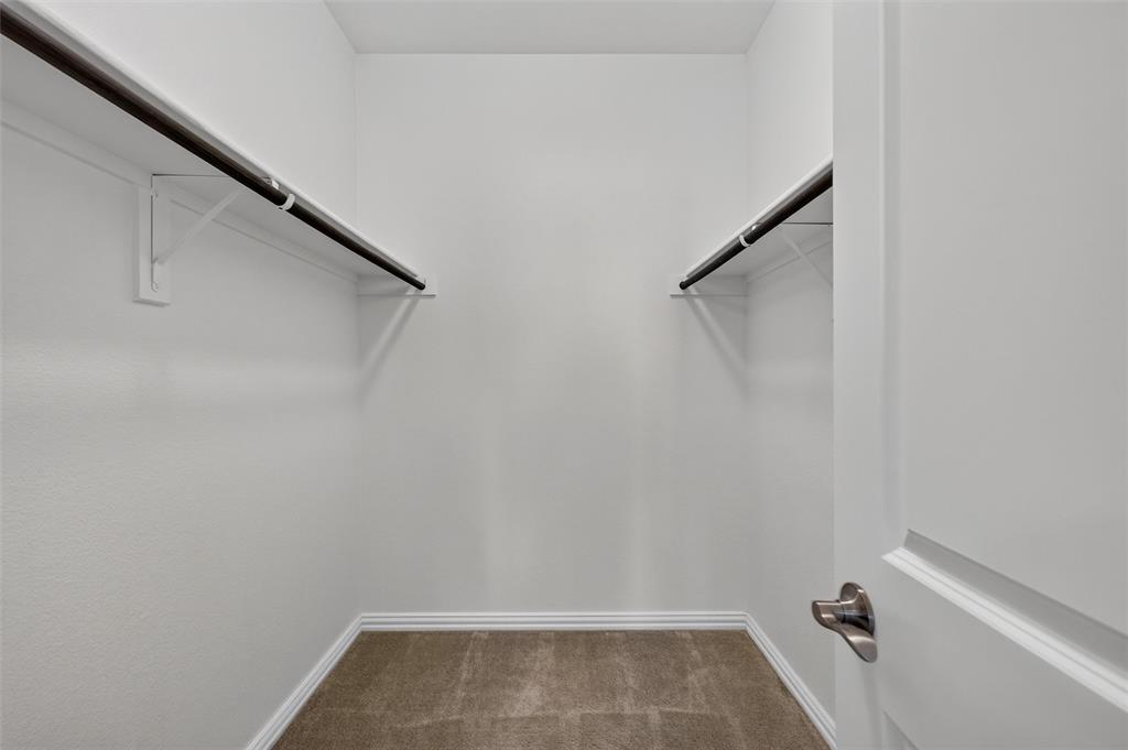 8715 Royal Star Road Rowlett, TX 75089 - Photo 28 of 39 Built-in closet rods with white wall brackets, neutral tone carpeting, and white wall paint