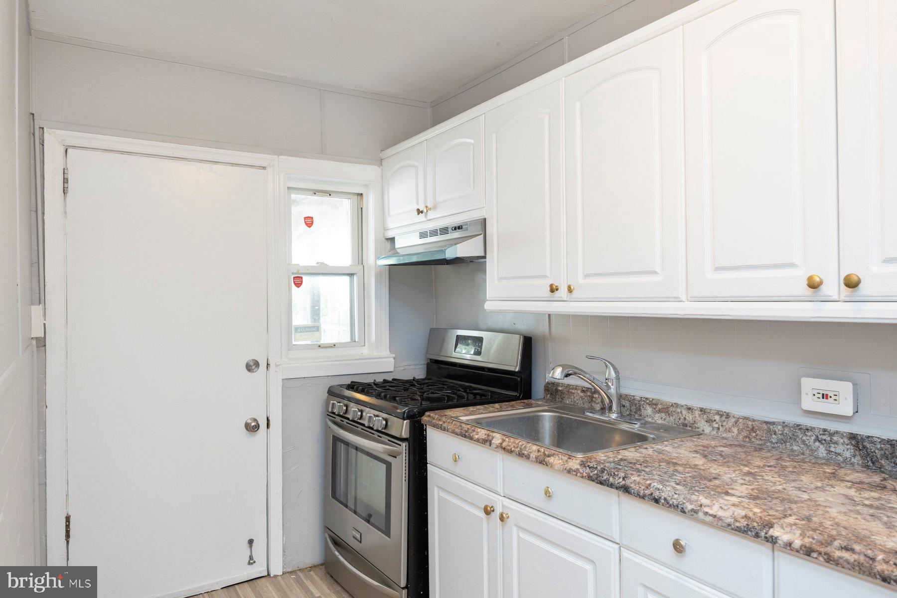 504 Roundview Road Baltimore, MD 21225 - Photo 4 of 26 a kitchen with granite countertop white cabinets and a sink