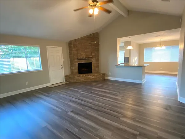 a view of an empty room with a fireplace and wooden floor