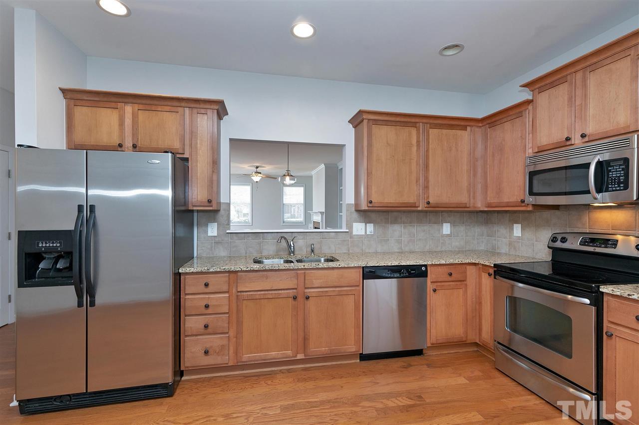 1340 Regulator Street Raleigh, NC 27603 - Photo 9 of 30 a kitchen with stainless steel appliances granite countertop a stove a sink and a refrigerator