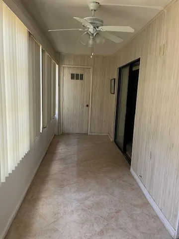 a view of a hallway with a chandelier fan and windows