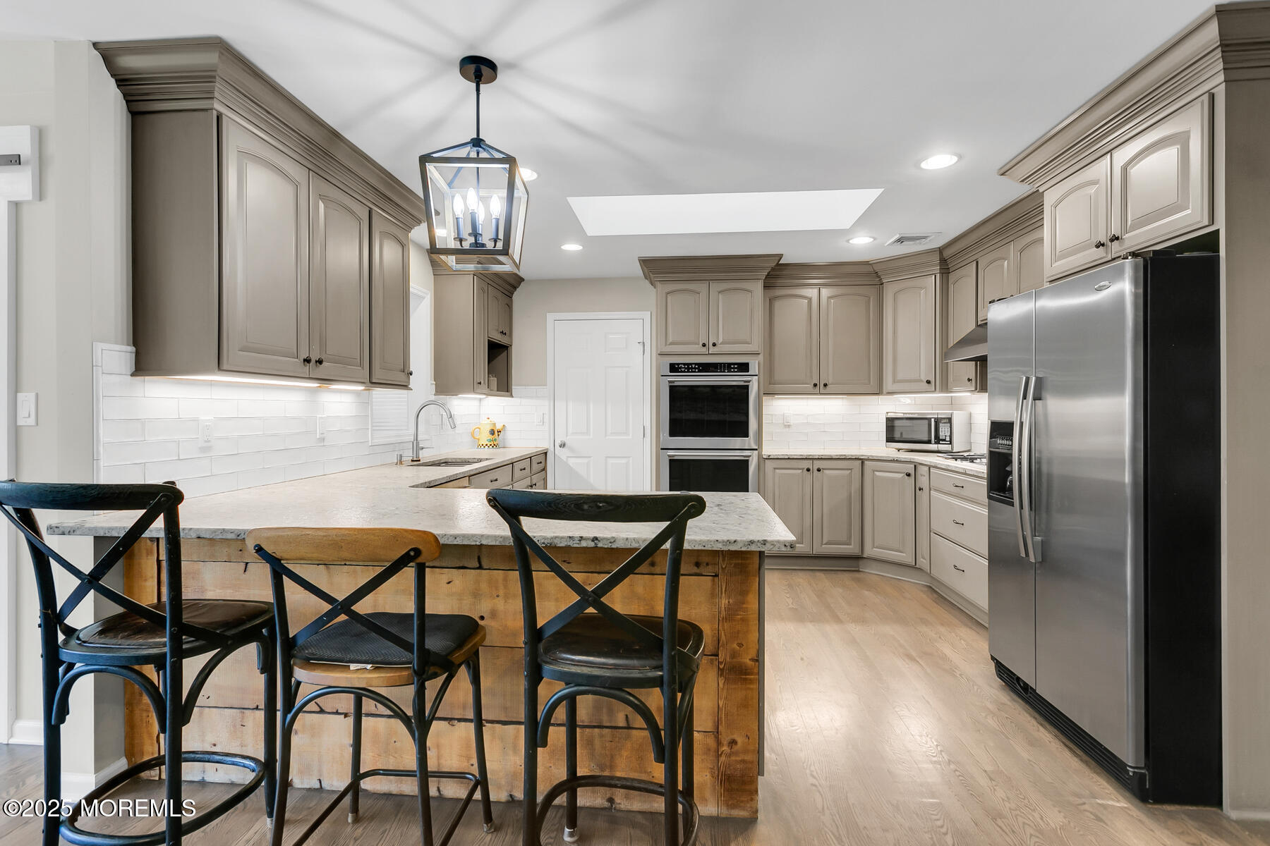 28 Colonial Terrace Colts Neck, NJ 07722 - Photo 17 of 57 a kitchen with stainless steel appliances kitchen island granite countertop a dining table chairs and a refrigerator