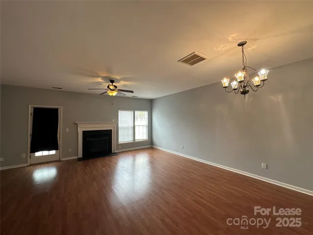 a view of a livingroom with a fireplace wooden floor and chandelier