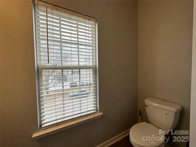 a white toilet sitting in a bathroom next to a window