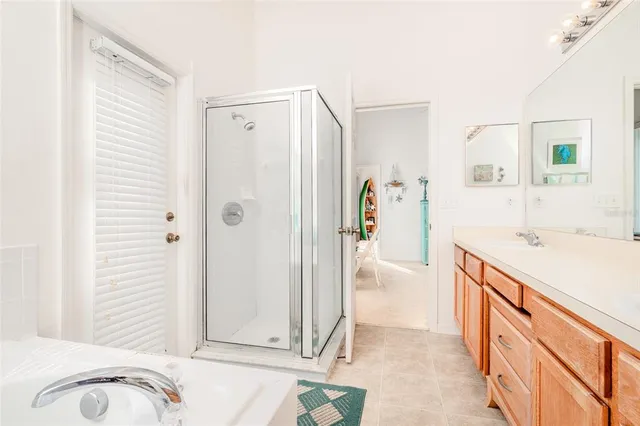 a bathroom with a granite countertop sink a mirror a bathtub and shower