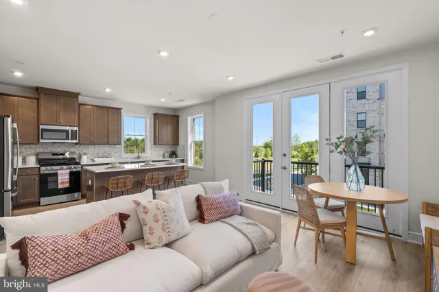 a living room with furniture wooden floor and kitchen view