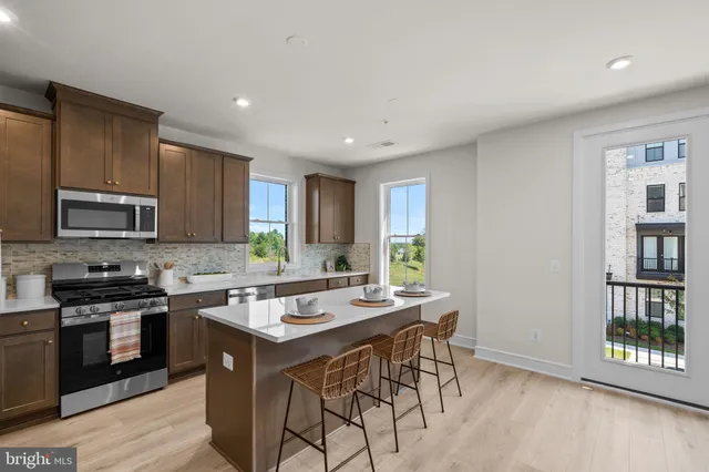 a kitchen with stainless steel appliances granite countertop a stove top oven a sink dishwasher a dining table and chairs with wooden floor