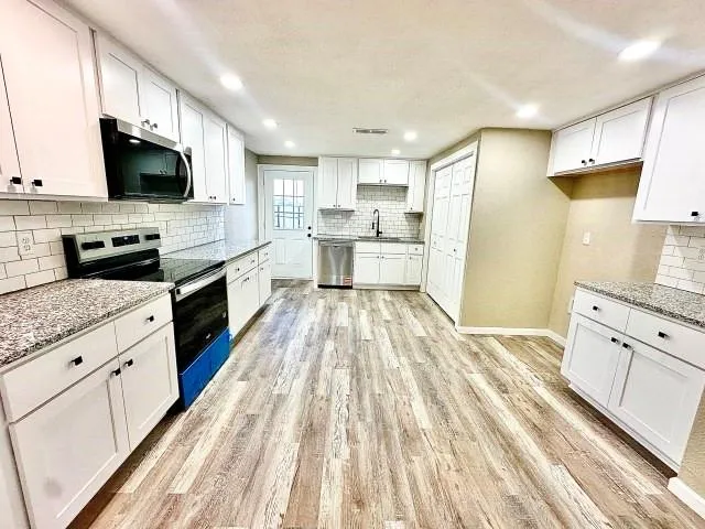 a large kitchen with cabinets wooden floor and stainless steel appliances