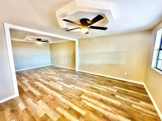 a view of a big room with wooden floor and chandelier fan