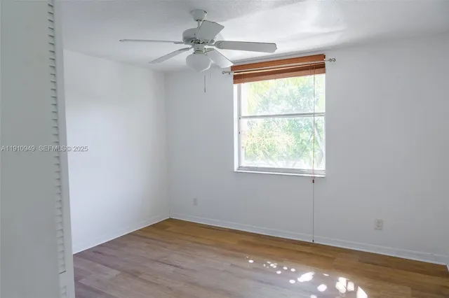 an empty room with wooden floor and a ceiling fan