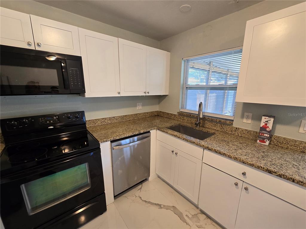 3406 Murrow Street New Port Richey, FL 34655 - Photo 11 of 21 a kitchen with granite countertop a stove a sink and a microwave