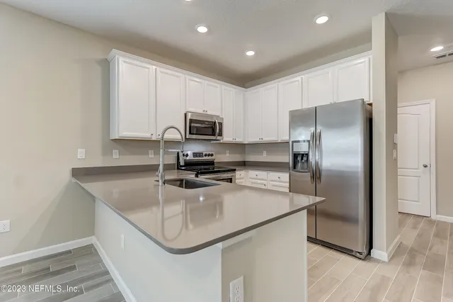 a kitchen with stainless steel appliances granite countertop a refrigerator a sink a stove a microwave and island