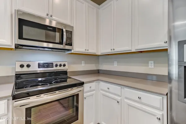 a kitchen with stainless steel appliances granite countertop grey cabinets a stove a sink and dishwasher
